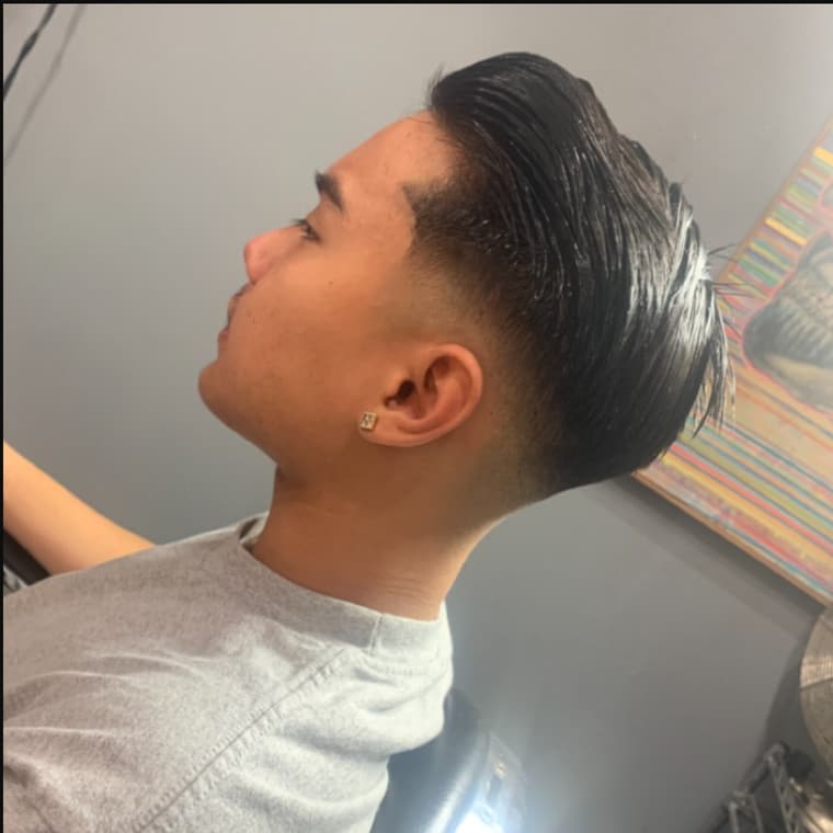 Slicked-back mid fade, finished and styled in the chair.